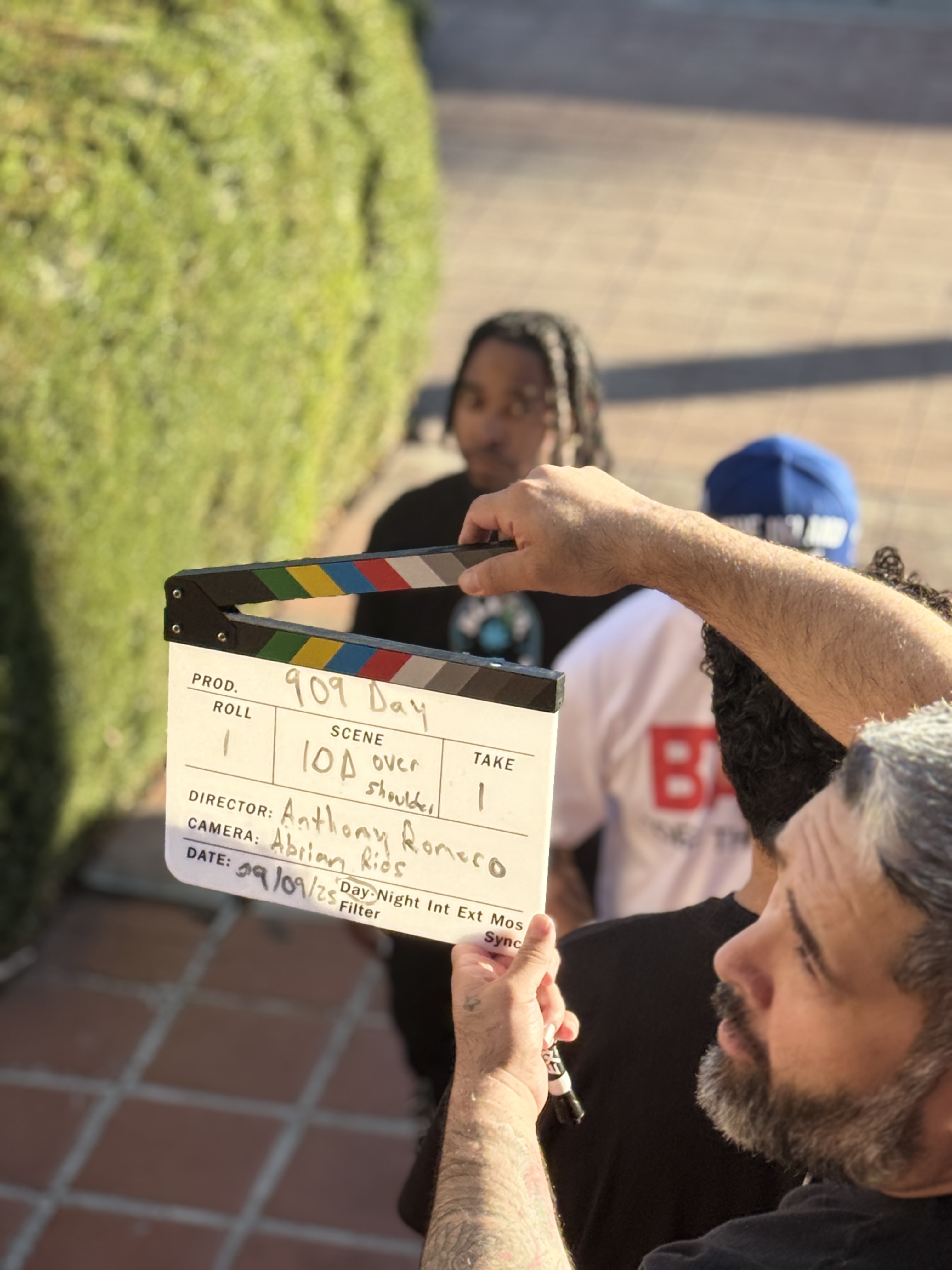 Behind the scenes of 909 Day Movie with a clapperboard and cast on set